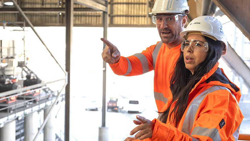 A man and a woman in safety clothes in a mining environment.