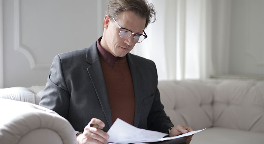 A man looking down on papers he's holding in his hands